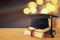 Image of graduation black hat over old books next to graduation on wooden desk. Education and back to school concept