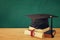 Image of graduation black hat over old books next to graduation on wooden desk. Education and back to school concept