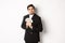 Image of greedy guy in black suit, holding money and unwilling to share, standing over white background