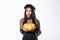 Image of grimacing asian woman in witch costume hate carve pumpkin for halloween, looking disappointed, standing over