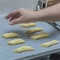 Image of a hand of a woman placing raw cookies on a waxed paper in a baking