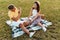 Image of handsome middle-aged man taking photo of smiling woman on cellphone while sitting in park