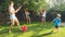 Image of happy children playing in the house backyard garden with water guns and garden hose. Family playing and having