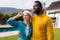 Image of happy diverse couple celebrating christmas standing outdoors in santa hats embracing