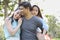 Image of happy family, sleepy daughter riding behind father while parents smiling during summer time in the park