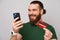 Image of happy handsome man with beard buying something online with credit card and smartphone