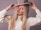 Image of happy lady dressed in sweater and hat isolated over grey-lilac background. Looking camera, posing