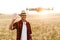 Image of happy man using drone while waving hand at cereal field