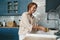 Image of happy redhead woman smiling while washing dishes at kitchen