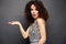 Image of happy young lady with afro curls hairstyle standing isolated over gray background. Looking camera pointing