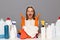 Image of hesitant angry woman with despair expression, sitting among different detergent, sitting at table with chemical products