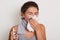 Image of ill allergic woman blowing running nose, having got flu or catch cold, sneezing in handkerchief, posing with closed eyes