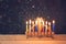 Image of jewish holiday Hanukkah background with menorah (traditional candelabra) Burning candles over black background