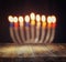 Image of jewish holiday Hanukkah background with menorah (traditional candelabra) Burning candles over wooden table
