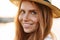 Image of joyful redhead woman in hat smiling and looking at camera
