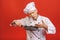 Image of joyful senior chief man in cook uniform smiling and holding frying pan isolated over red wall background