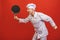 Image of joyful senior chief man in cook uniform smiling and holding frying pan isolated over red wall background