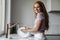 Image of joyful woman smiling while washing dishes in modern kitchen