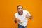 Image of joyous guy 30s in t-shirt rejoicing and showing thumbs up while standing,  over yellow background