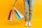 An image of legs, a woman after shopping stands with a lot of multi-colored bags, on a yellow background