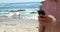 Image of like over midsection of biracial woman using smartphone at beach