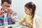 Image of a little girl doing science experiments in the laboratory with father who looks through magnifying glass. Dad and