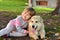 Image of little girl hugging white puppy dog laying on park ground