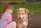 Image of little girl touching white puppy dog laying on park ground