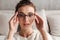 Image of lovely young woman in eyeglasses resting on sofa at home