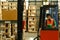 Image of male warehouse worker moving cardboard boxes of goods with forklift between rows of tall shelves