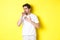 Image of man with covid-19 or flu symptoms, coughing and feeling sick, standing over yellow background