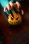 Image of man`s hands with pumpkin jack sitting at wooden table