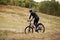 Image of mauntain bike cyclist in meadow near forest, side view of sporty male riding bike during his vacation, enjoying his hobby