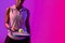Image of midsection of african american female tennis player in violet and pink neon lighting