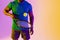 Image of midsection of african american male tennis player in violet and yellow neon lighting