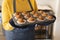 Image of midsection of african american woman with tray of freshly made cupcakes