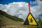 Image of mountain slope, cloudy sky and warning sign