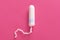 Image of one unused clean tampon being isolated over pink background, product for menstruation, disposable feminine hygiene thing