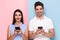 Image of optimistic couple using cell phones together, isolated