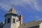 Image of peaks of roof and weathervane with brilliant blue skies beyond