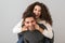 Image of pleased couple having fun and while man piggybacking woman, over gray background