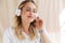 Image of pleased elegant blonde woman listening to music in headphones
