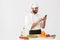 Image of positive chef man in uniform smiling and holding smartphone while cooking vegetable salad