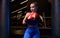 Image of a powerful sportswoman wrestler. Posing in a blue tracksuit and red boxing gloves. The concept of wrestling and boxing