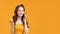 Image of a pretty cheery smiling asian woman posing isolated over yellow wall background talking by mobile phone