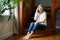 Image pretty happy caucasian woman sitting on wooden stairs indoors at home