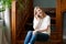 Image pretty happy caucasian woman sitting on wooden stairs indoors at home