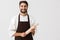 Image of professional chief man in cook uniform smiling and holding kitchen wooden rolling pin