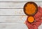 Image of raw sea buckthorn in a ceramic bowl and a cup of hot seabuckthorn tea on rustic wooden backgroud. Autumn backdrop.