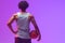 Image of rear view of biracial basketball player with basketball on neon purple background